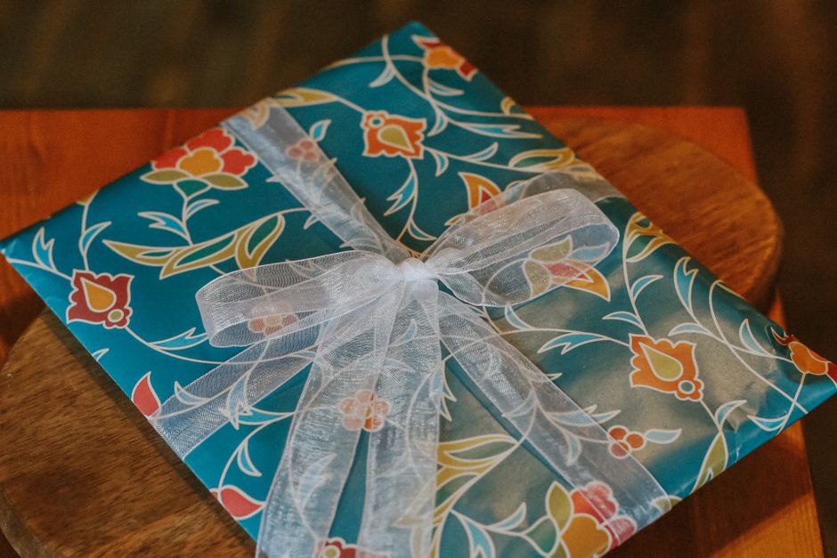 A beautifully wrapped gift box next to a smartphone showing a banking app