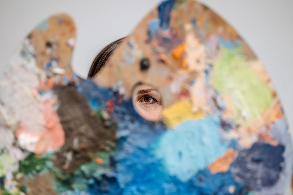 A creative artist sketching in a notebook, surrounded by colorful paints and unique decorations