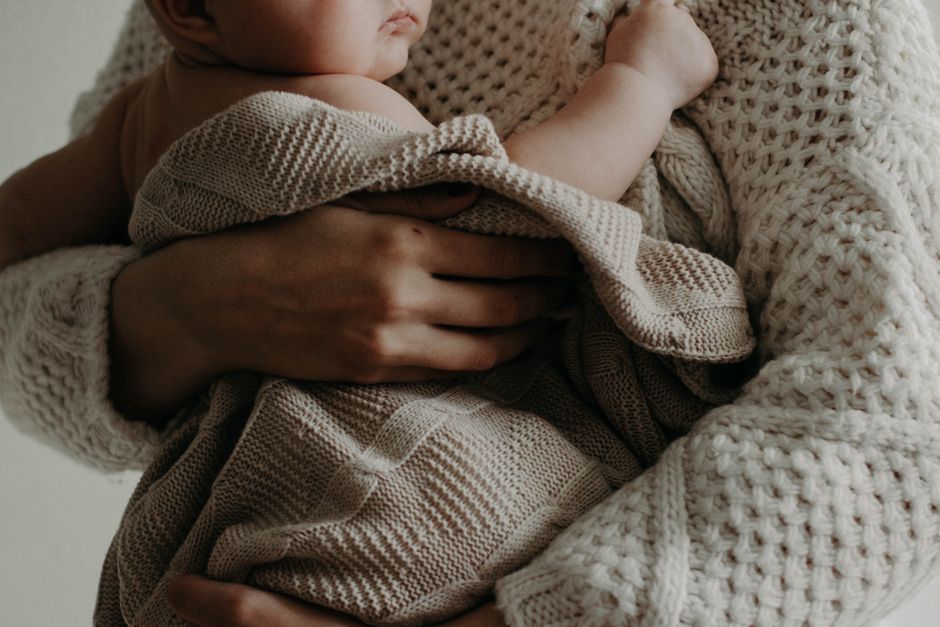 A mother holding her newborn baby close, smiling warmly