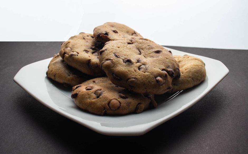 A plate of freshly baked chocolate chip cookies on a rustic wooden table