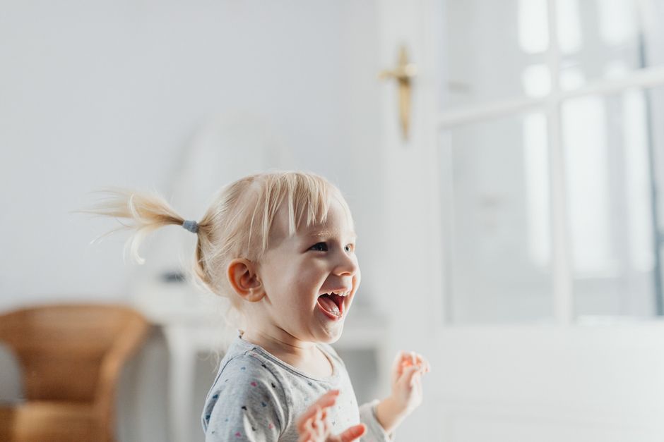 A smiling toddler named Theo playing with wooden building blocks in a sunny room