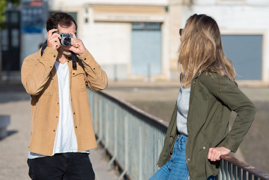 A couple taking a selfie on a mountain summit with camera gear and outdoor backdrop