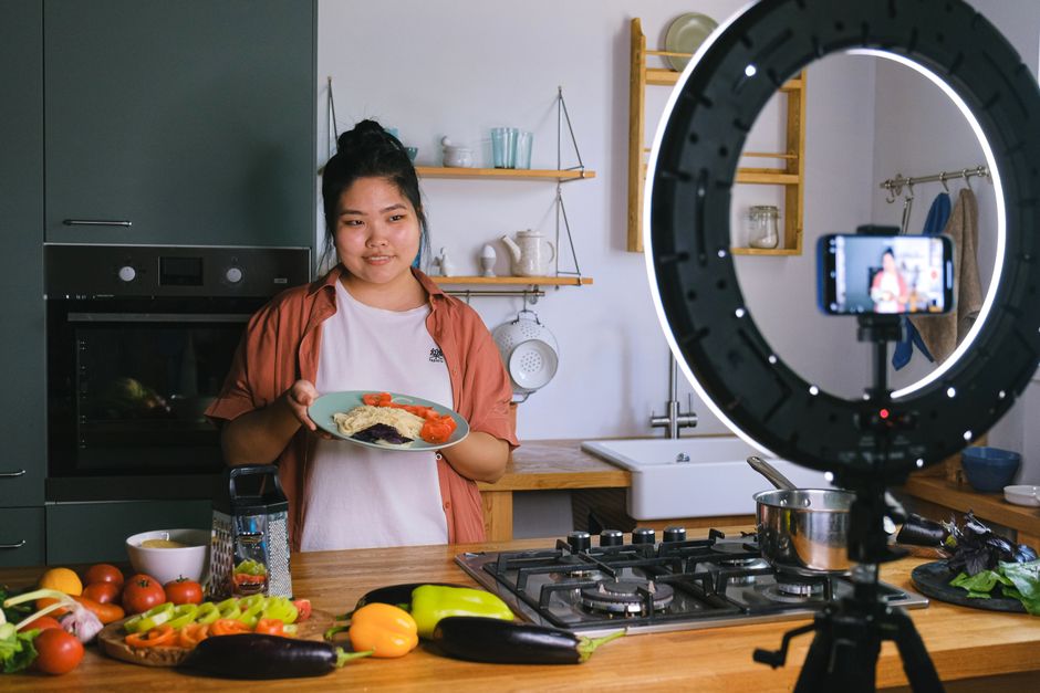 A creator filming cooking and lifestyle content with a ring light and smartphone setup