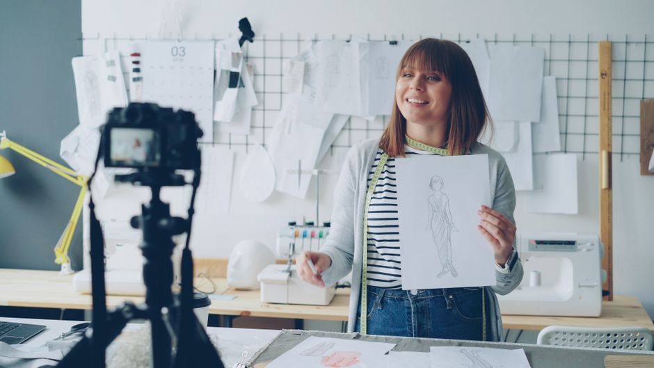 A creator sketching brainstorm maps and notes for cool TikTok usernames on a desk next to a smartphone showing the TikTok profile screen.