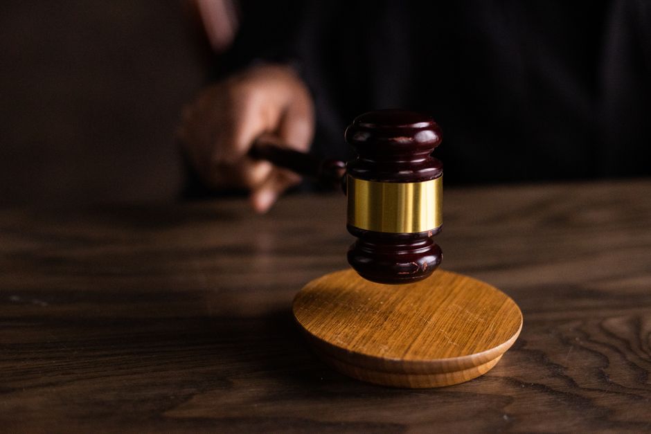 A gavel resting next to a smartphone displaying paused video files