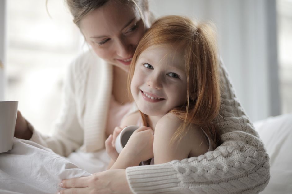 A smiling mom recording a candid parenting video for TikTok on a ring light