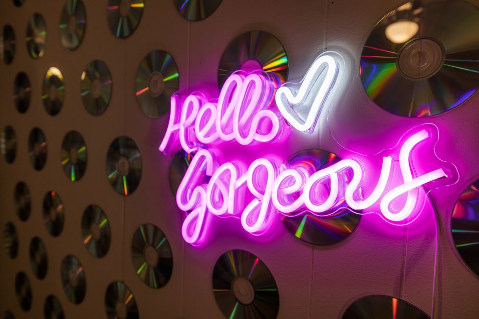 A stylish neon sign glowing in a dark room displaying various cool abbreviations like Sare, Sal, and Rah