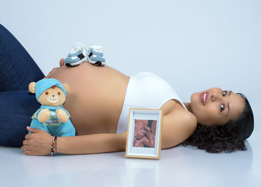An expectant mother recording a short-form video on a smartphone while holding nursery color swatches and baby name cards