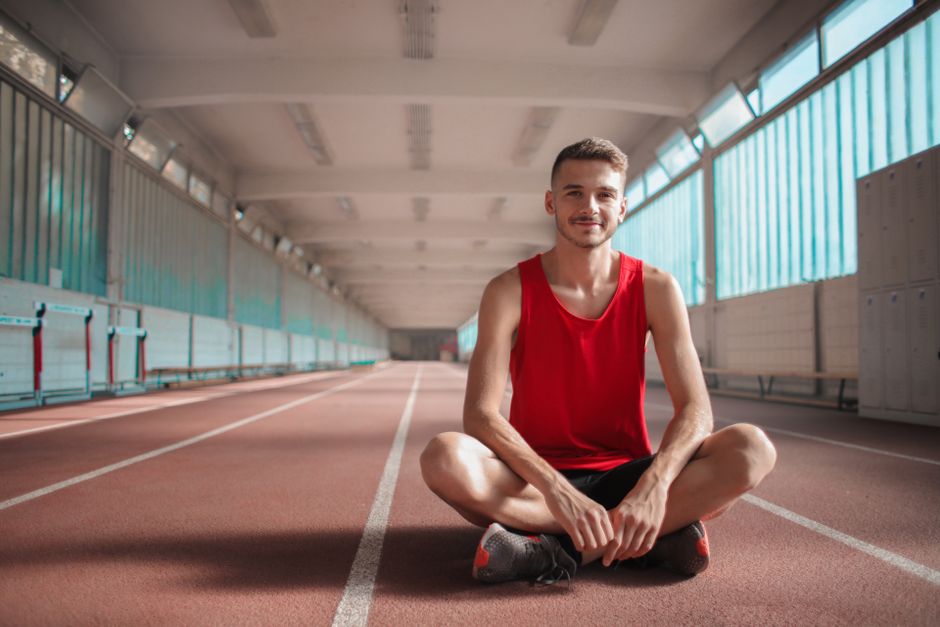 Athletic creator posing in front of gym equipment showing their TikTok profile on a smartphone screen