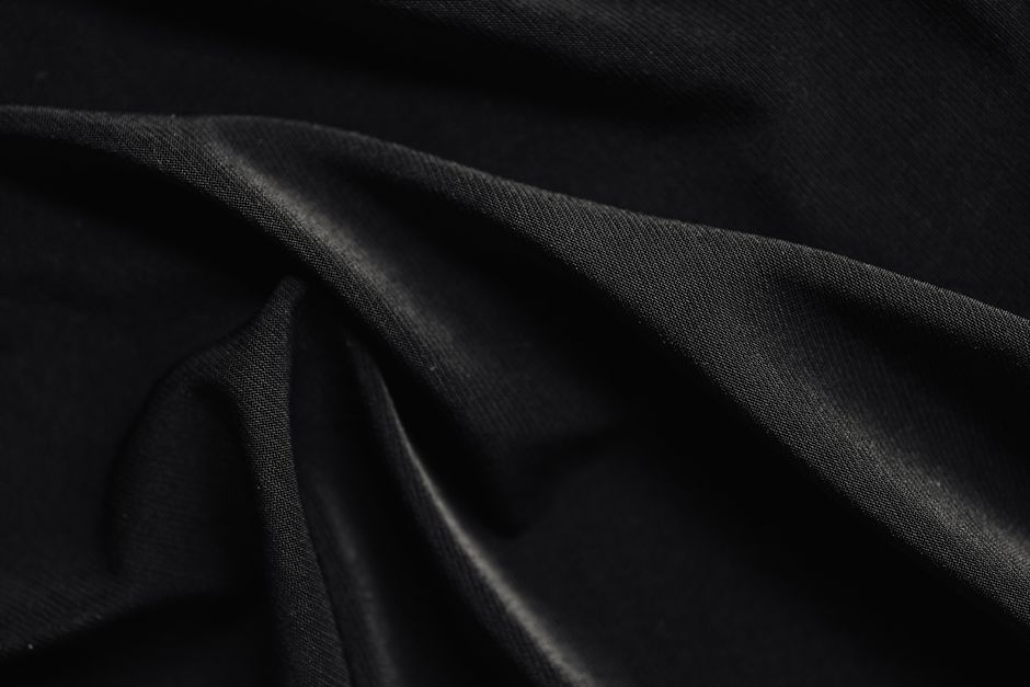 Close-up of black lace gloves holding a vintage porcelain teacup against dark velvet fabric