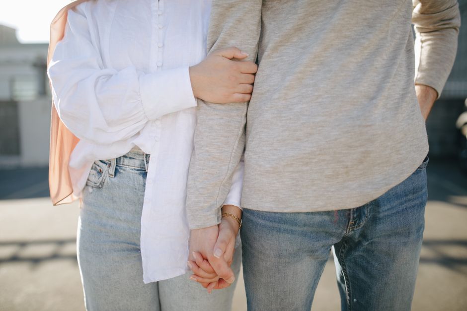 Couple holding two smartphones side-by-side displaying complementary social media profile pages