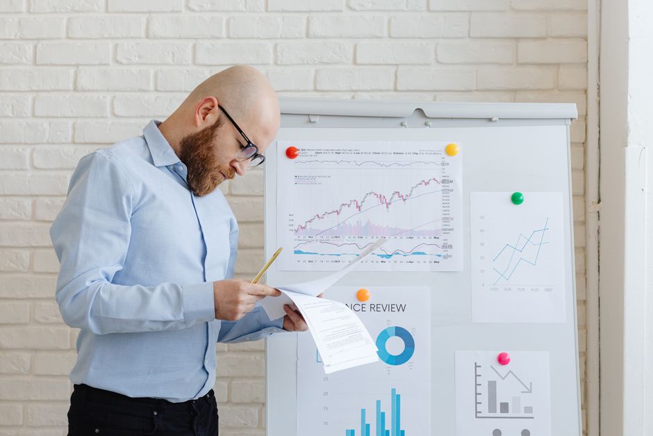 Hombre analizando gráficos en un monitor mientras graba contenido financiero para redes sociales