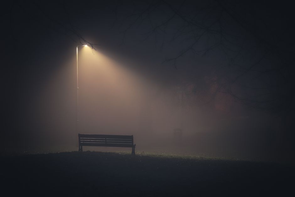 Lone streetlamp glowing in dark blue midnight fog
