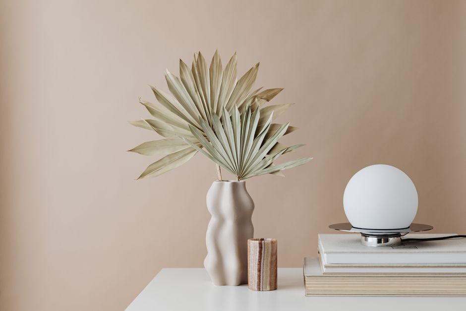Minimalist aesthetic flat lay of modern wireless headphones, an iced green tea, and open journal on a marble table