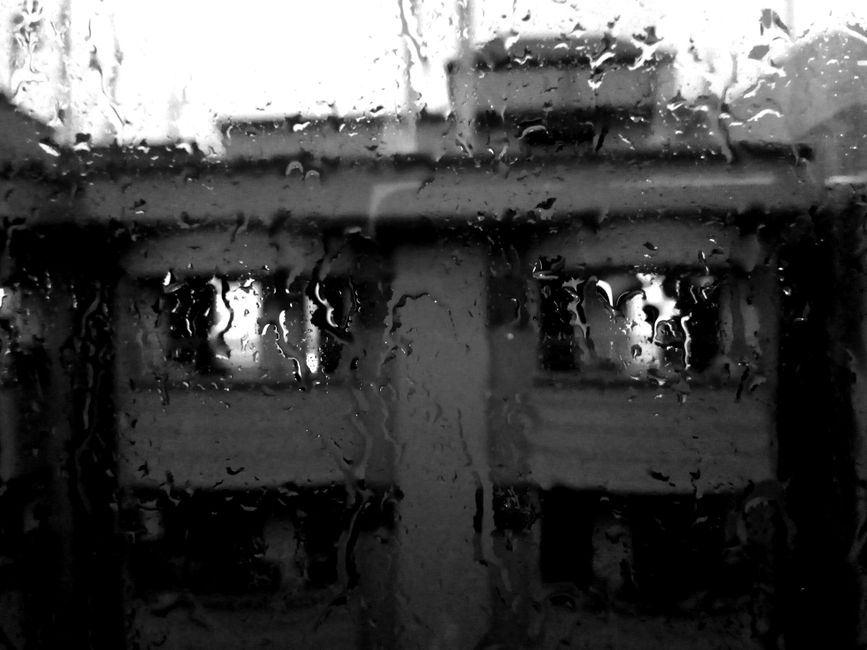 Moody rainy window overlooking city streetlights with condensation and reflections
