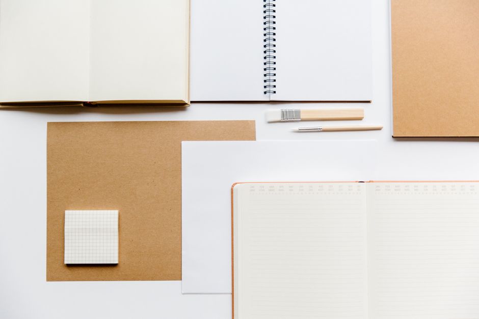 Notebook open on a wooden table showing brainstorming notes and mind maps for social media handles