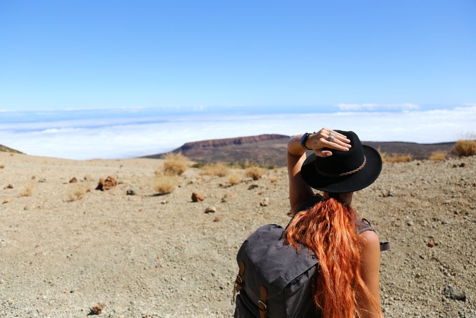 Solo traveler standing atop a scenic mountain ridge at sunrise filming mobile content