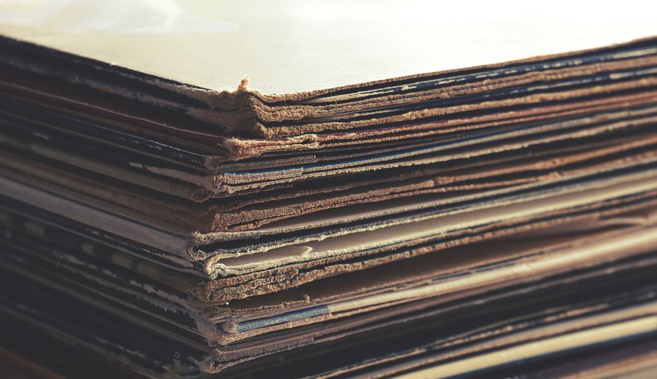 Stack of vintage vinyl records, cassette tapes, and a 35mm film camera