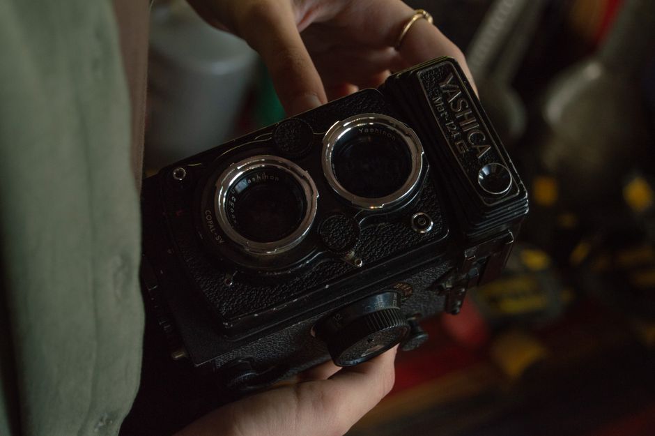 Vintage twin-lens reflex camera resting on a classic film script and satin gloves